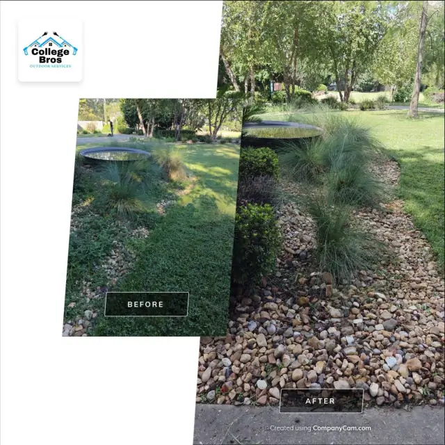 River-rock landscape bed with a birdbath and fountain grass beside a sunlit lawn