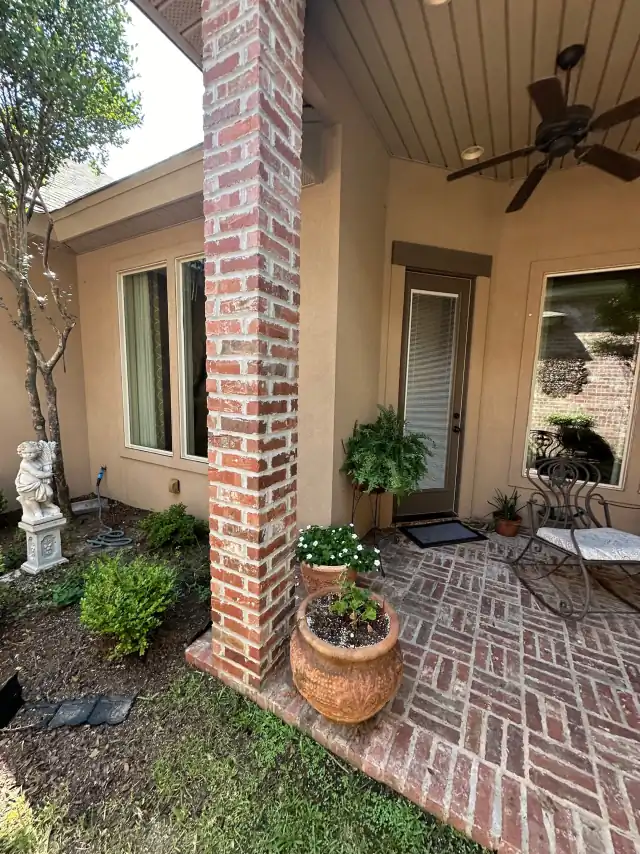 Herringbone brick paver walkway with a column and potted flowers after pressure washing