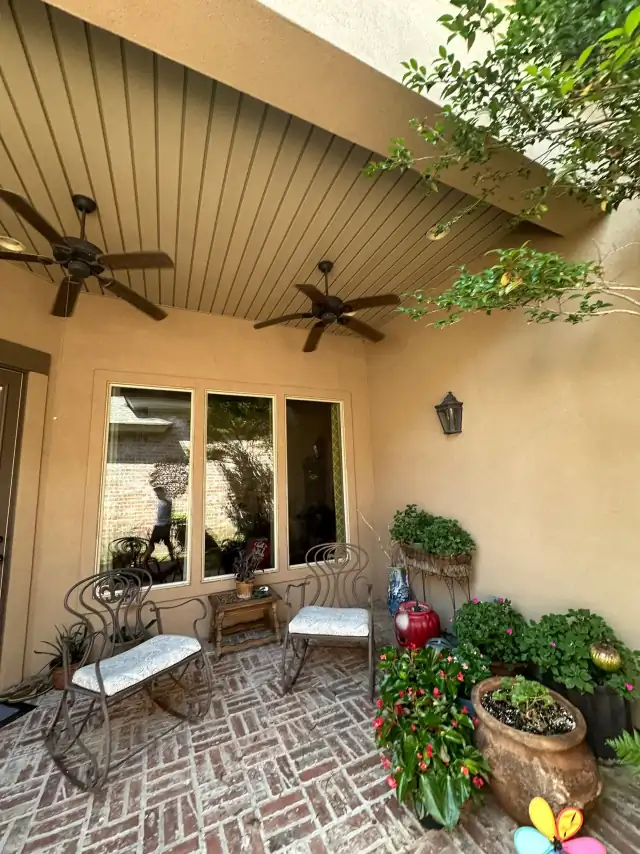 Clean upscale patio with ceiling fans, outdoor seating, and potted flowers after pressure washing