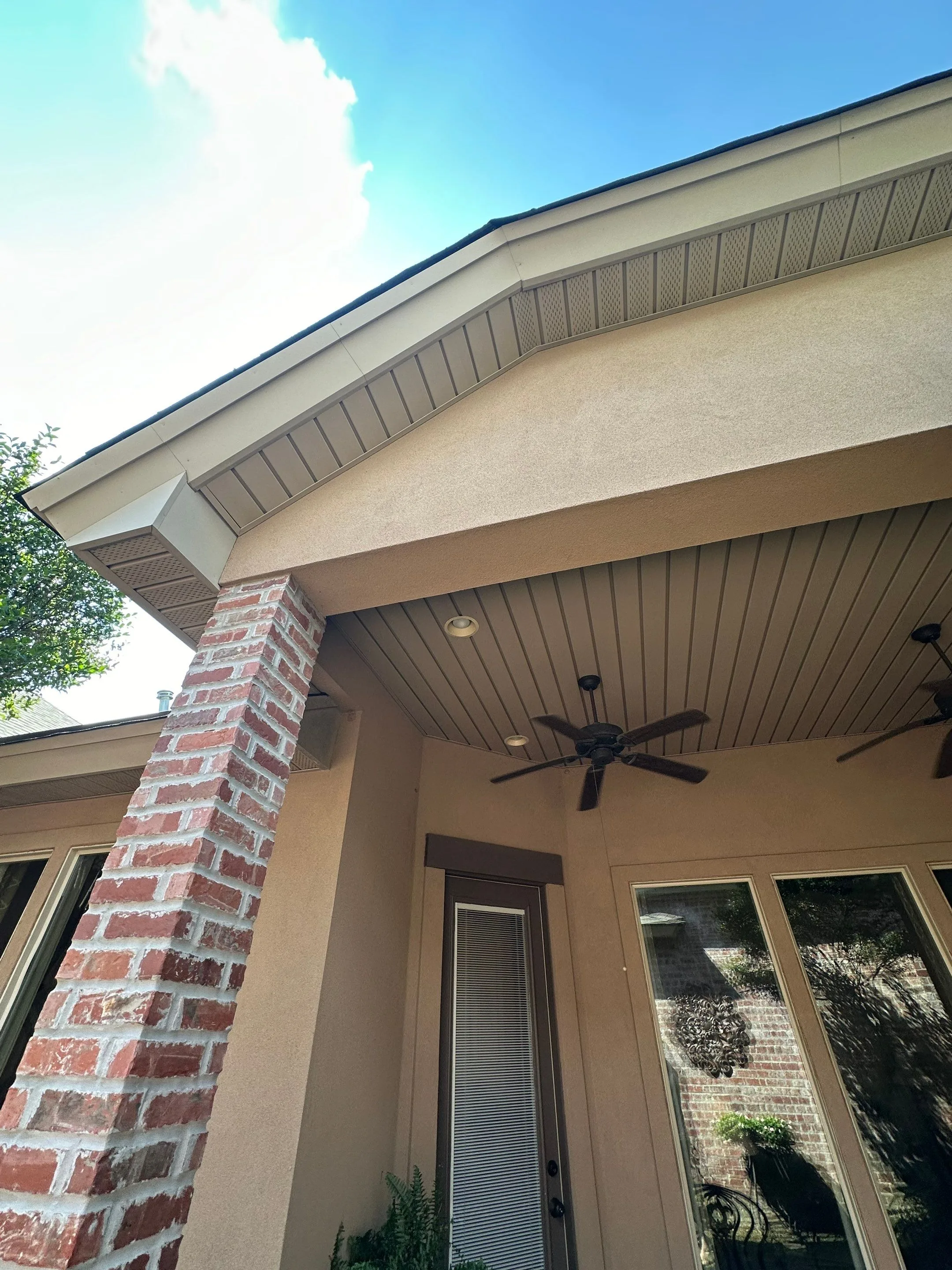 Clean gable soffit and porch ceiling with fans after an exterior soft wash