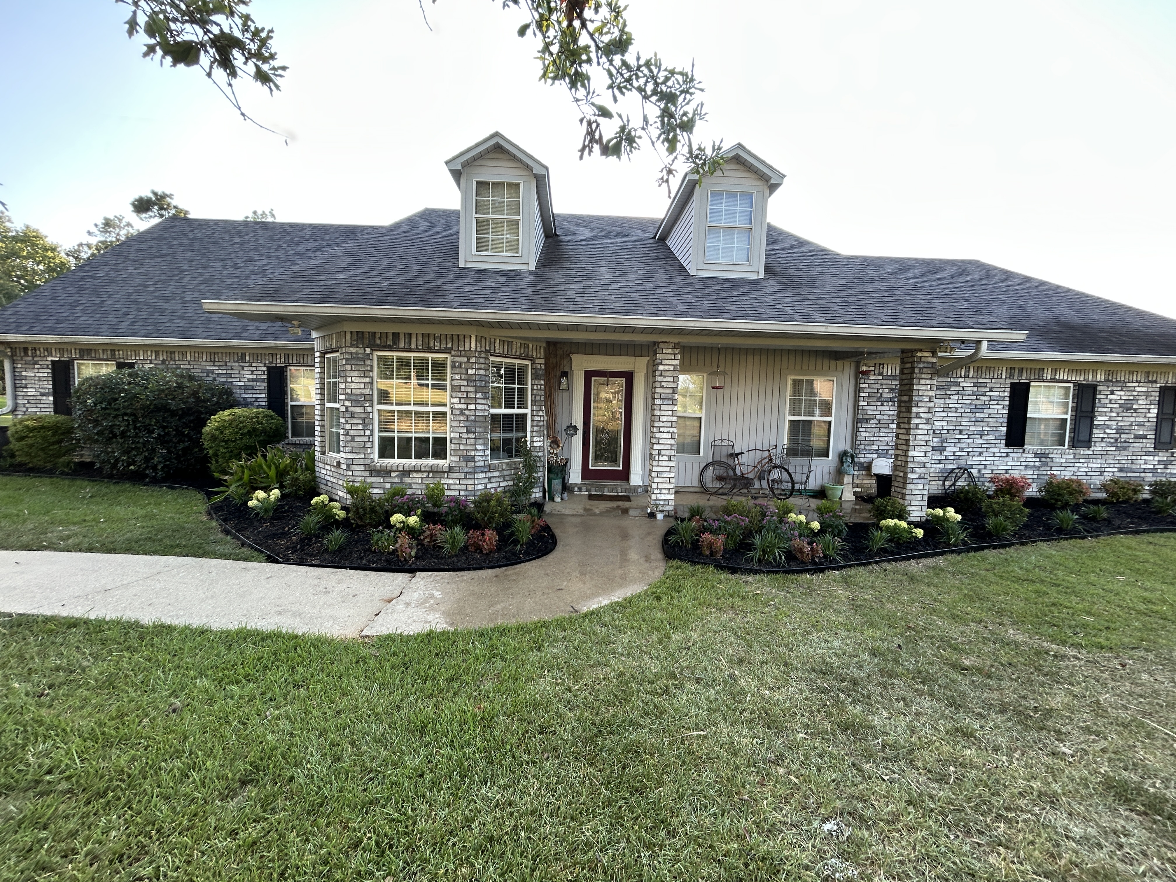 Completed College Bros front landscape-bed refresh with black mulch, clean edging, and new plantings